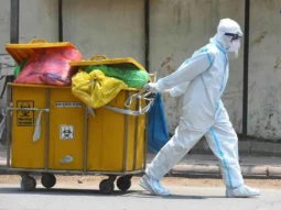 a man wearing protective gear and towing a cart with biohazard waste